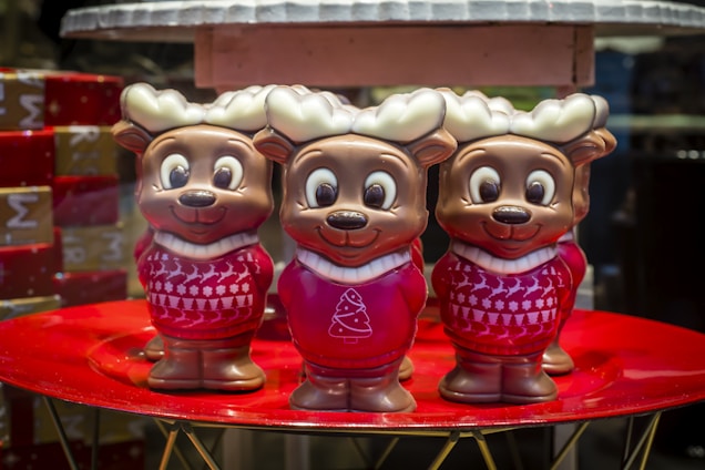 A cozy scene showing a group of plush reindeer with different expressions sitting together on a wooden shelf.