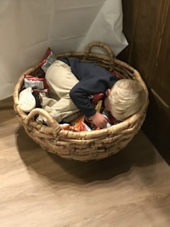 A toddler happily exploring a sensory basket filled with natural textures and bright colors.