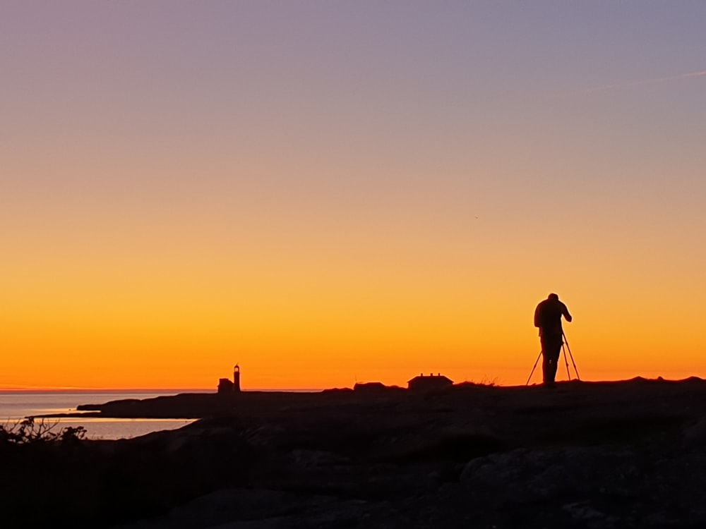 silhouette photo of man standing near calm body of water