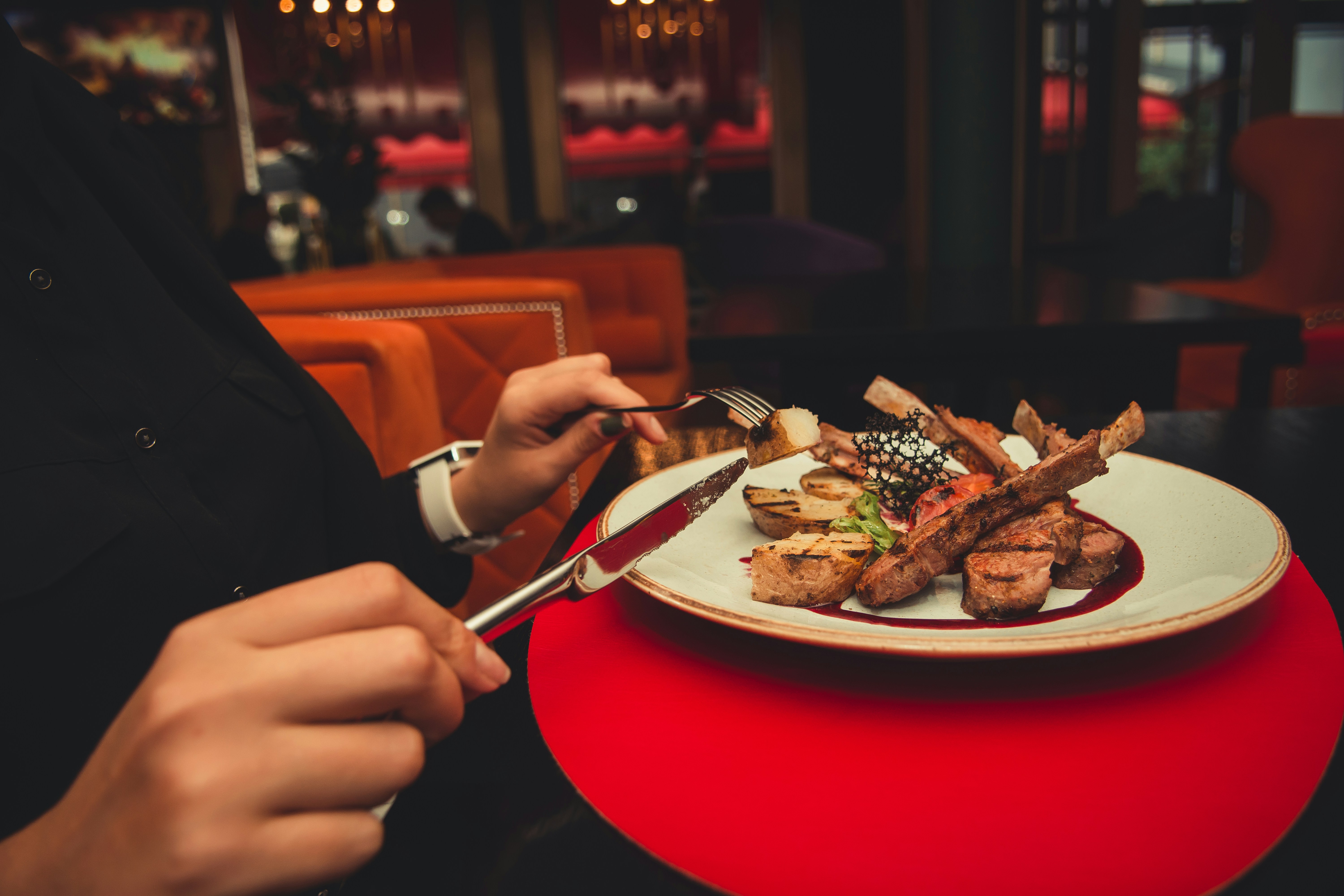Diner cutting into lamb on a plate at night