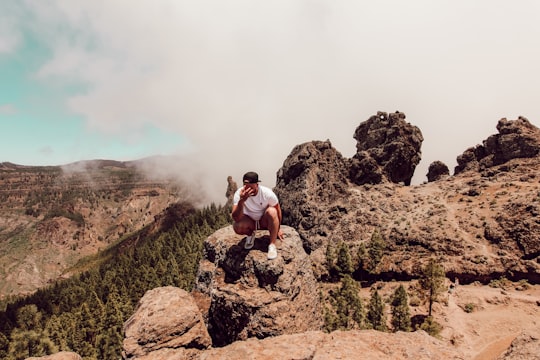 man sitting on rock formation in Roque Nublo Spain
