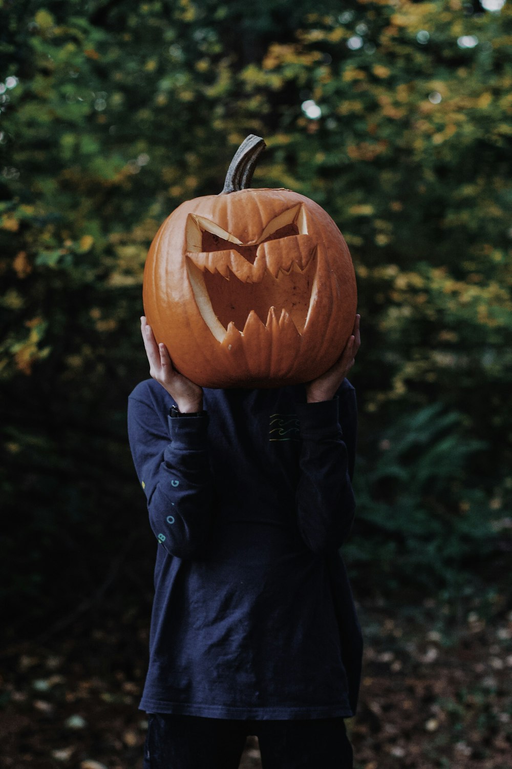 una persona sosteniendo una calabaza tallada sobre su cabeza