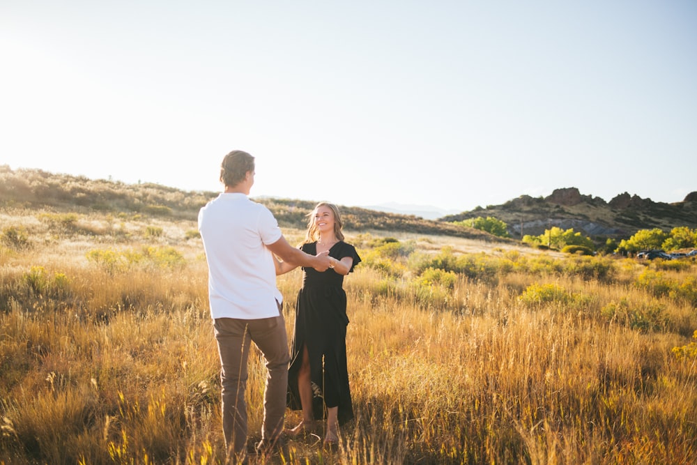 man and woman standing on brown field