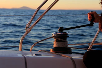 A close-up of hands skillfully handling sailing ropes aboard a yacht at sunset.
