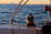 Close-up of a ship's davit crane smoothly lowering a lifeboat into the water at sunset.