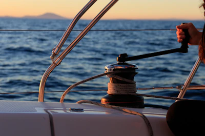 A close-up of hands skillfully handling sailing ropes aboard a yacht at sunset.