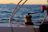 Close-up of a ship's davit crane smoothly lowering a lifeboat into the water at sunset.