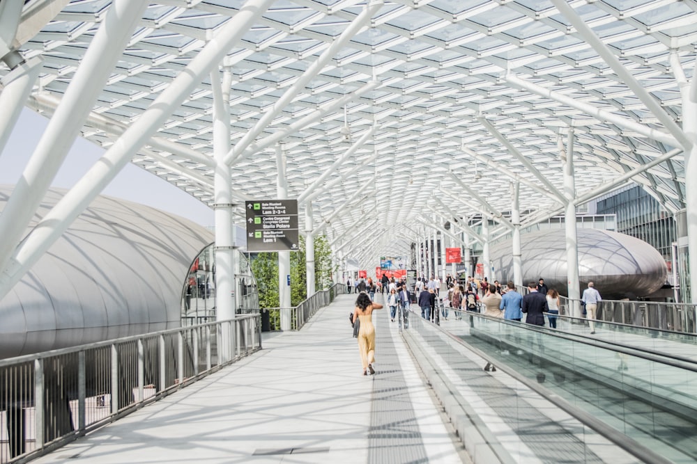 a group of people walking down a walkway next to a train