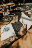 A student inking a travel-inspired tattoo on a sunlit veranda.