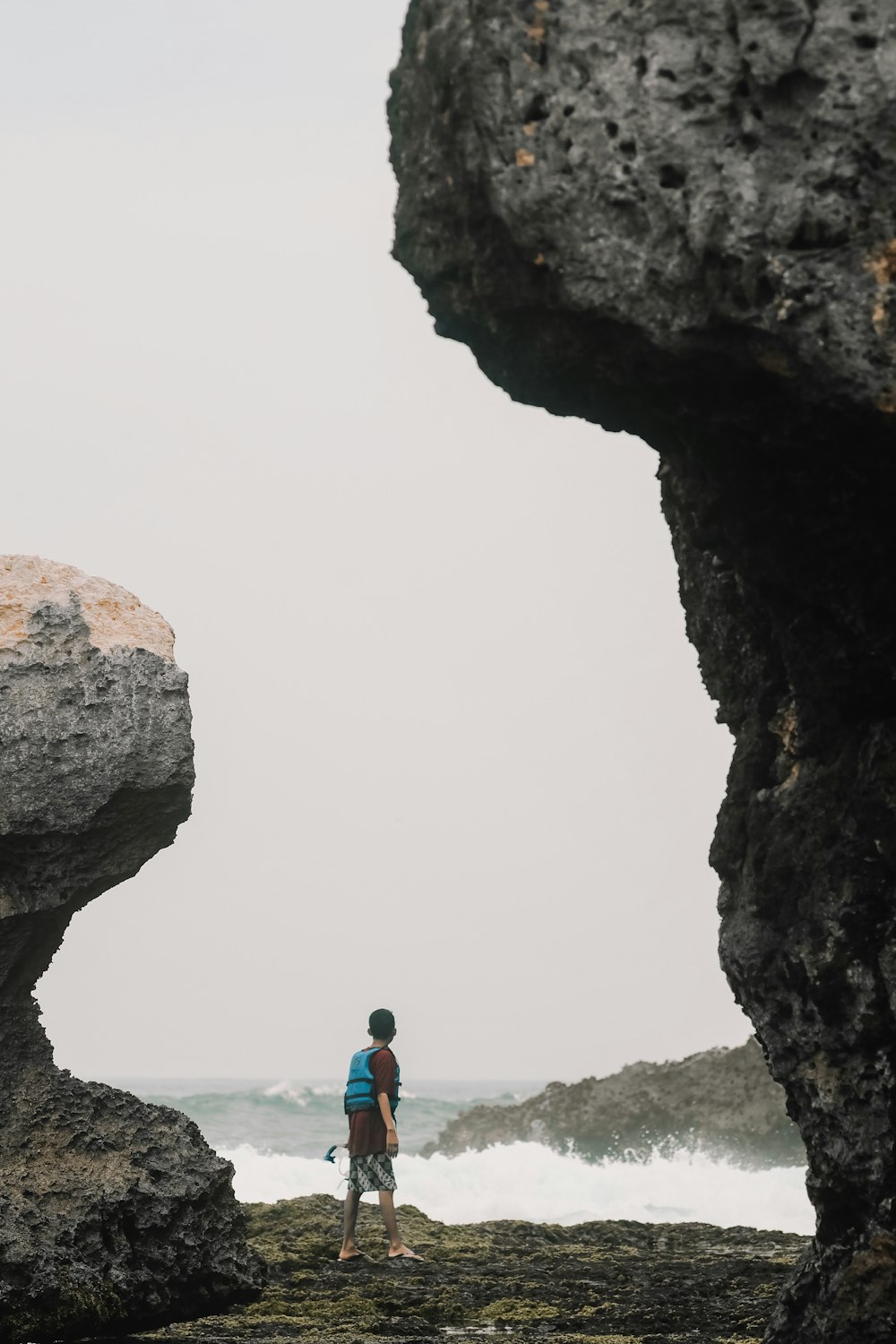 a man standing on top of a rocky beach next to the ocean