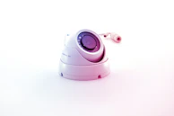 Minimalist dome camera with a glossy black finish against a light gray background.