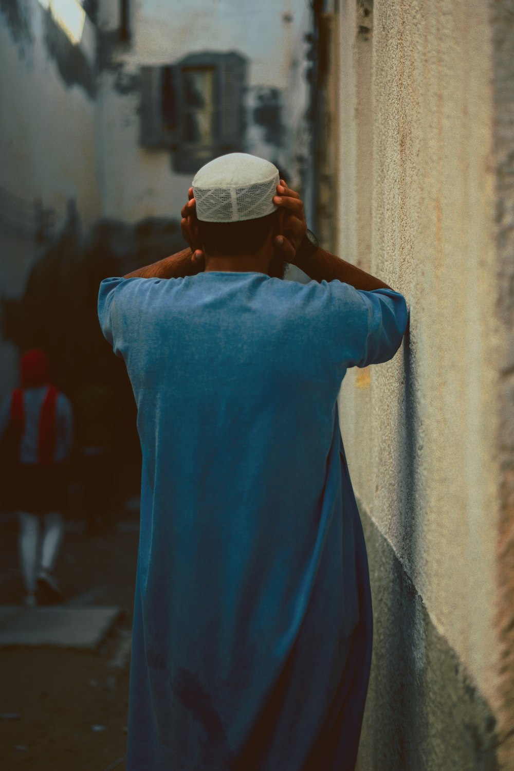 man standing near brown wall holding his head