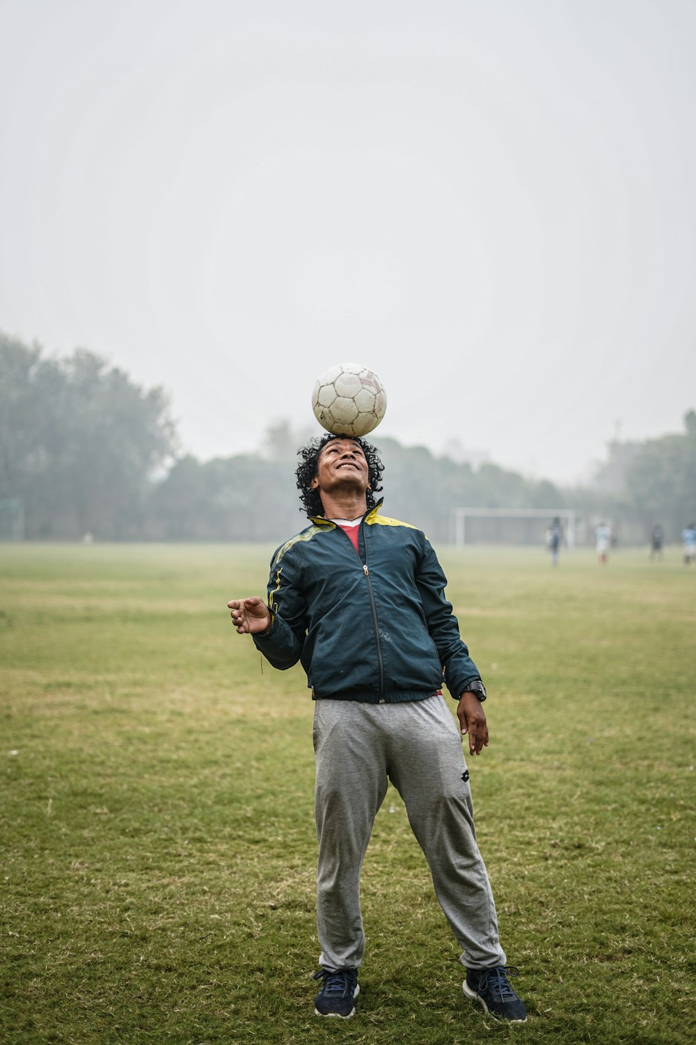 man balancing a soccer ball on his head