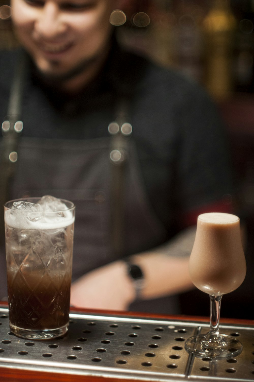 man wearing black overall near the clear long stem wine glasses