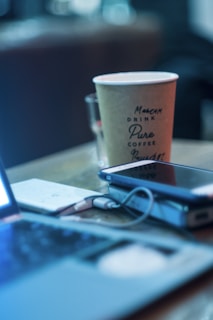 A coffee cup next to a smartphone showing affiboost blog homepage in electric blue.