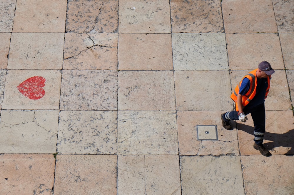 homem vestindo colete reflexivo laranja andando no caminho durante o dia