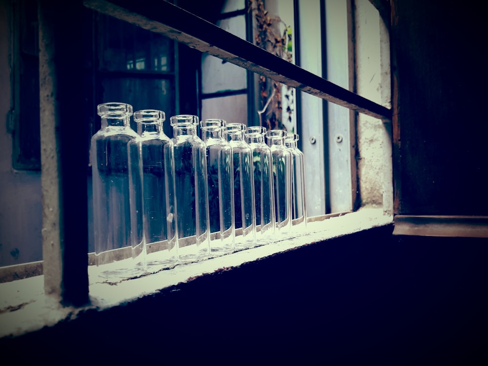 empty clear glass bottles near wall