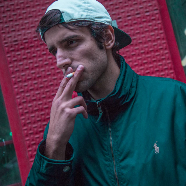 A man in London wearing a teal Polo Ralph Lauren zip up jacket and a cap