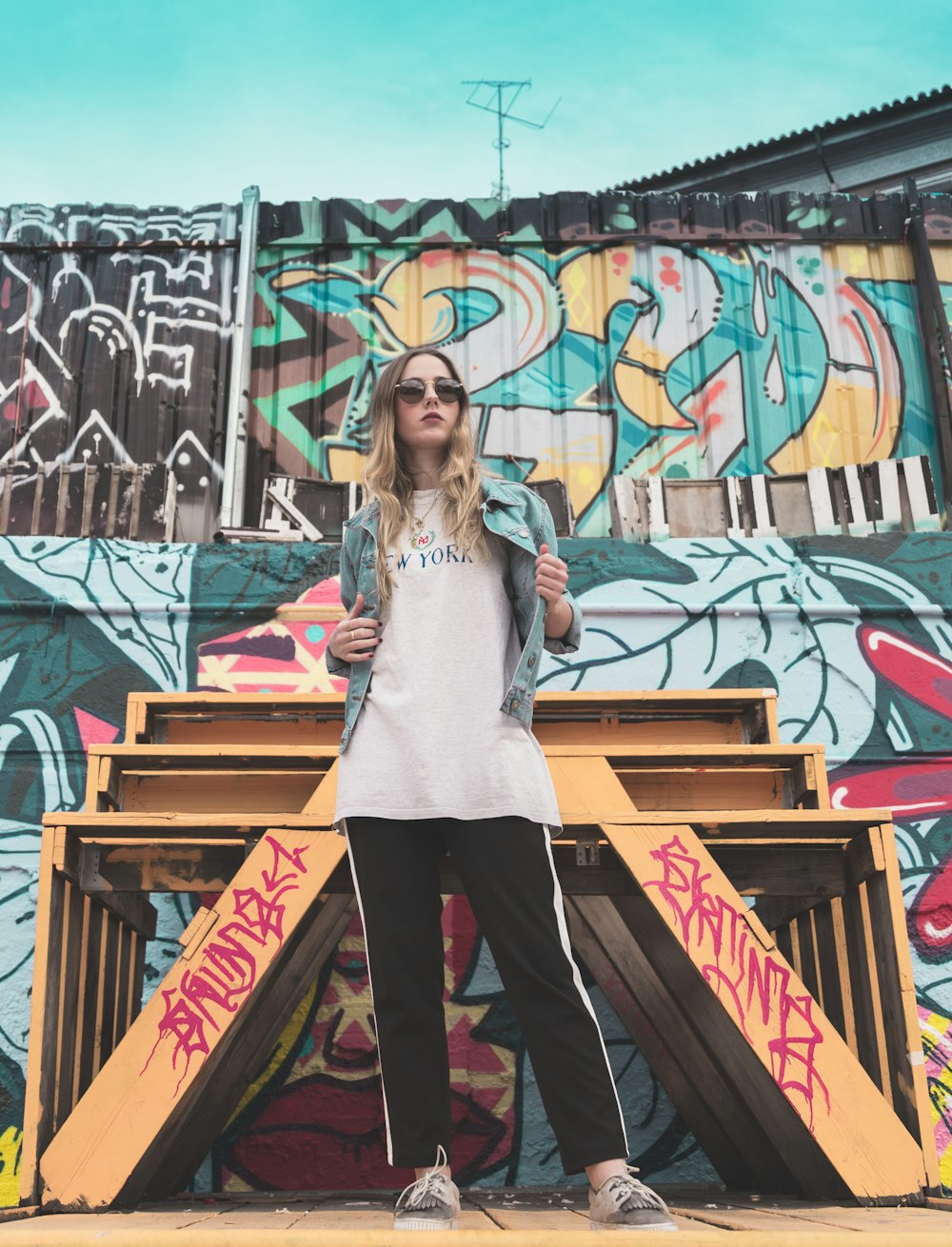 woman wearing blue denim jacket standing near wall during daytime