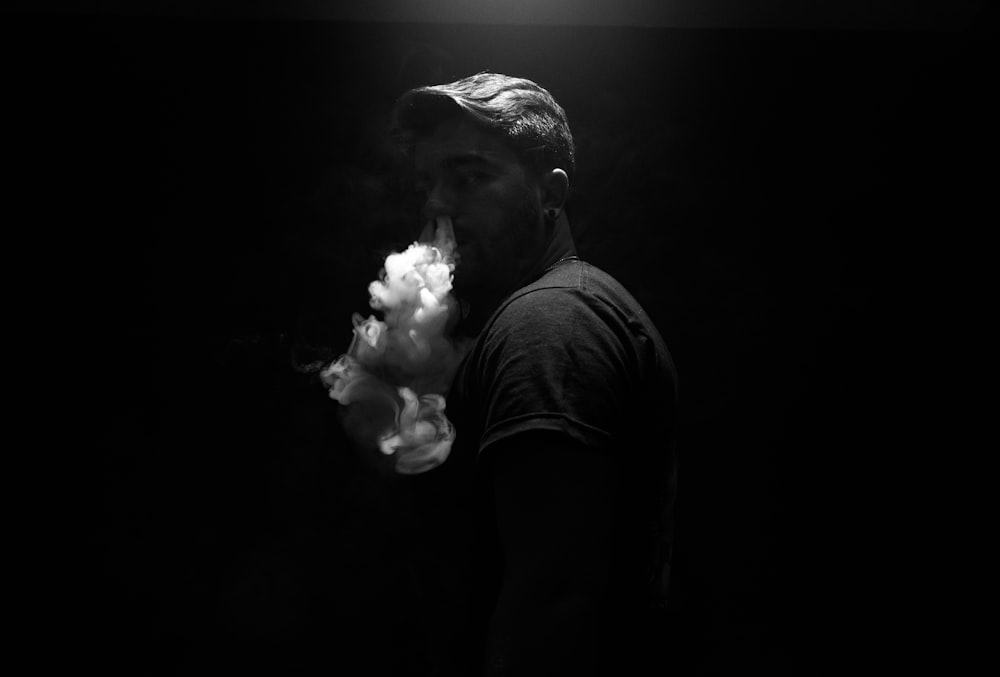 煙を吐き出す男のグレースケール写真