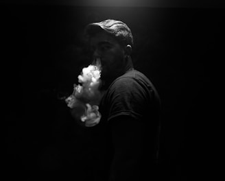 grayscale photo of man exhaling smoke