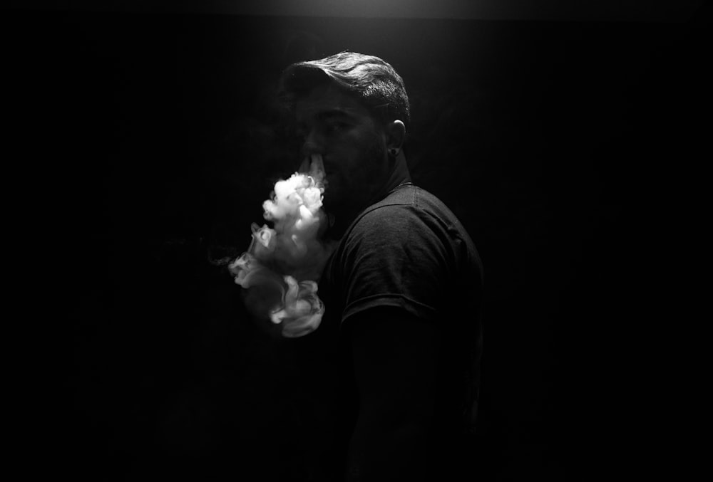 grayscale photo of man exhaling smoke