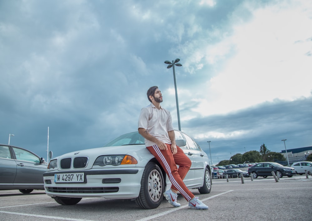 man sitting on white BMW car