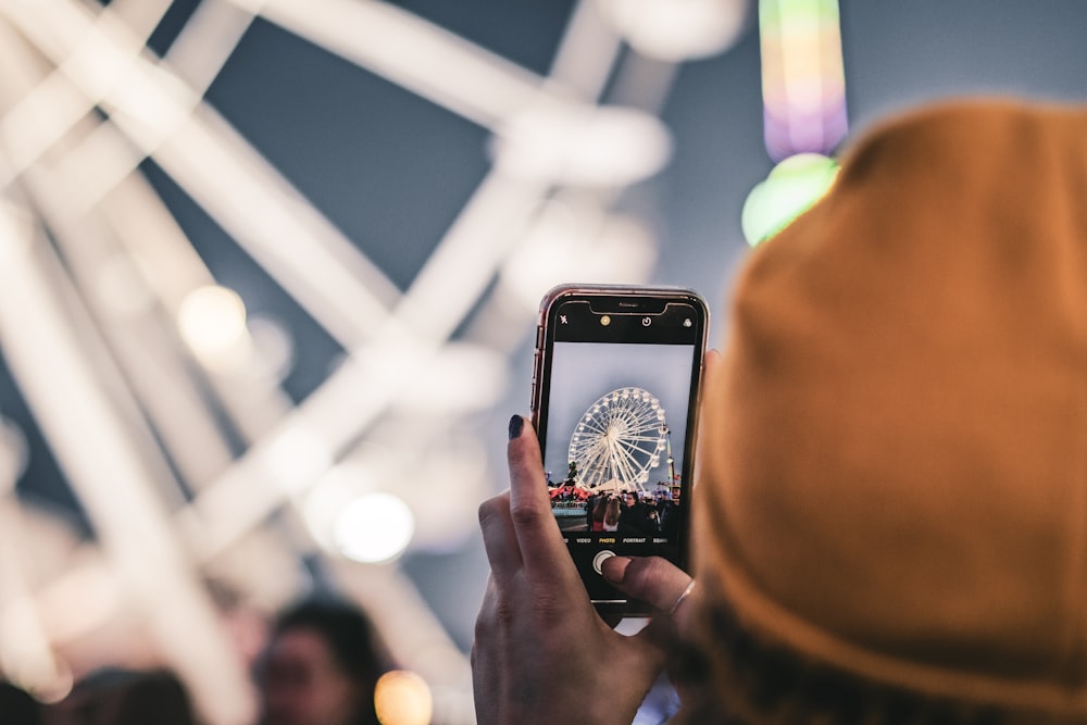 person taking photo of Ferris Wheel at night