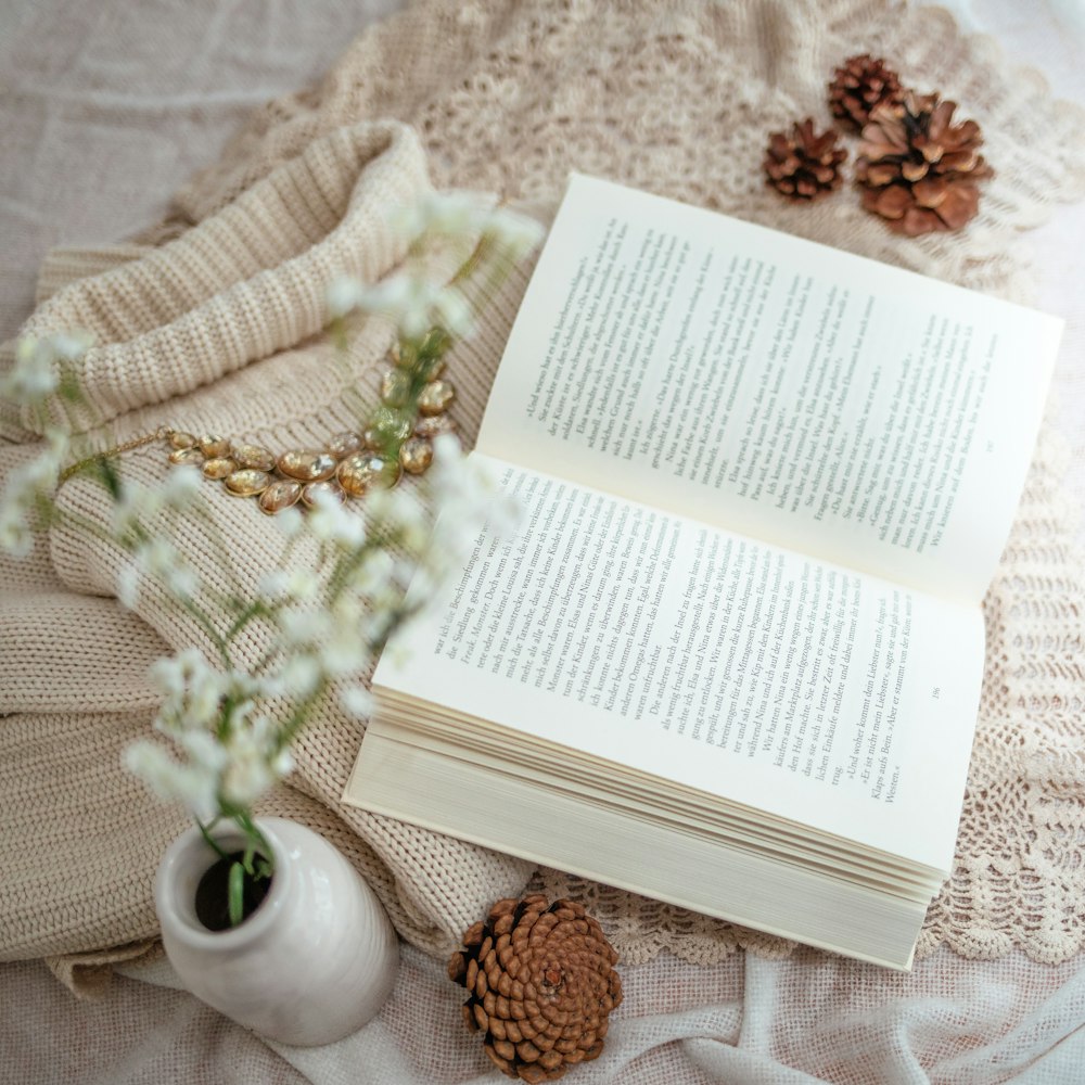 open book besie white flower on top of knit sweater