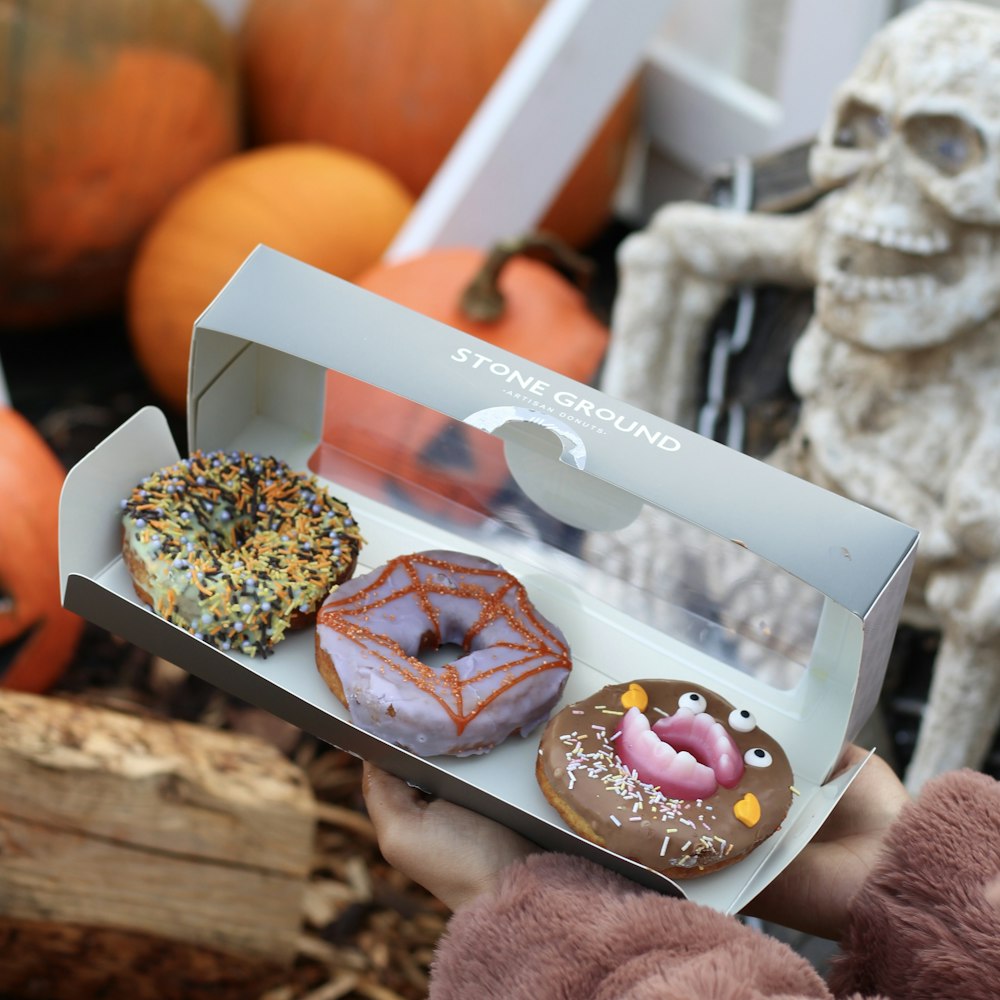 three assorted-color Stone Ground doughnuts on box