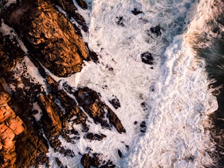 Smooth drone footage of ocean waves crashing against rugged cliffs.