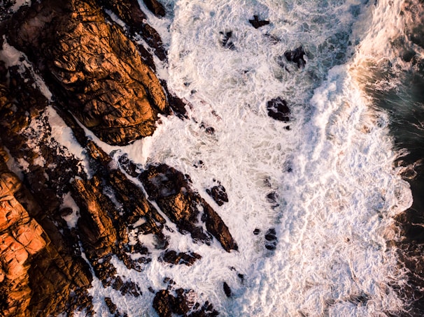 Smooth drone footage of ocean waves crashing against rugged cliffs.