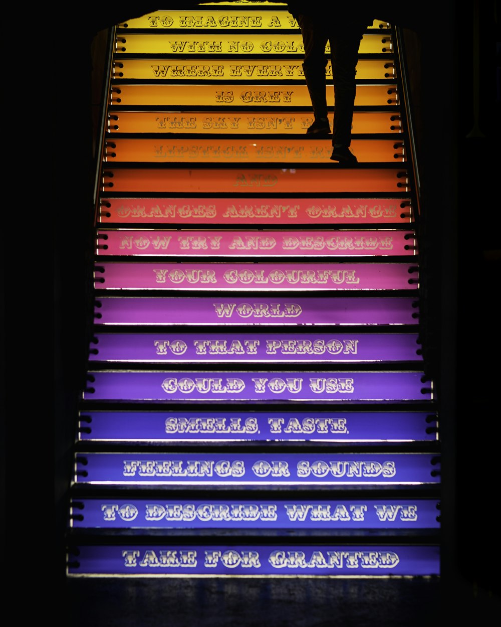 person walking through stairs with assorted-color steps
