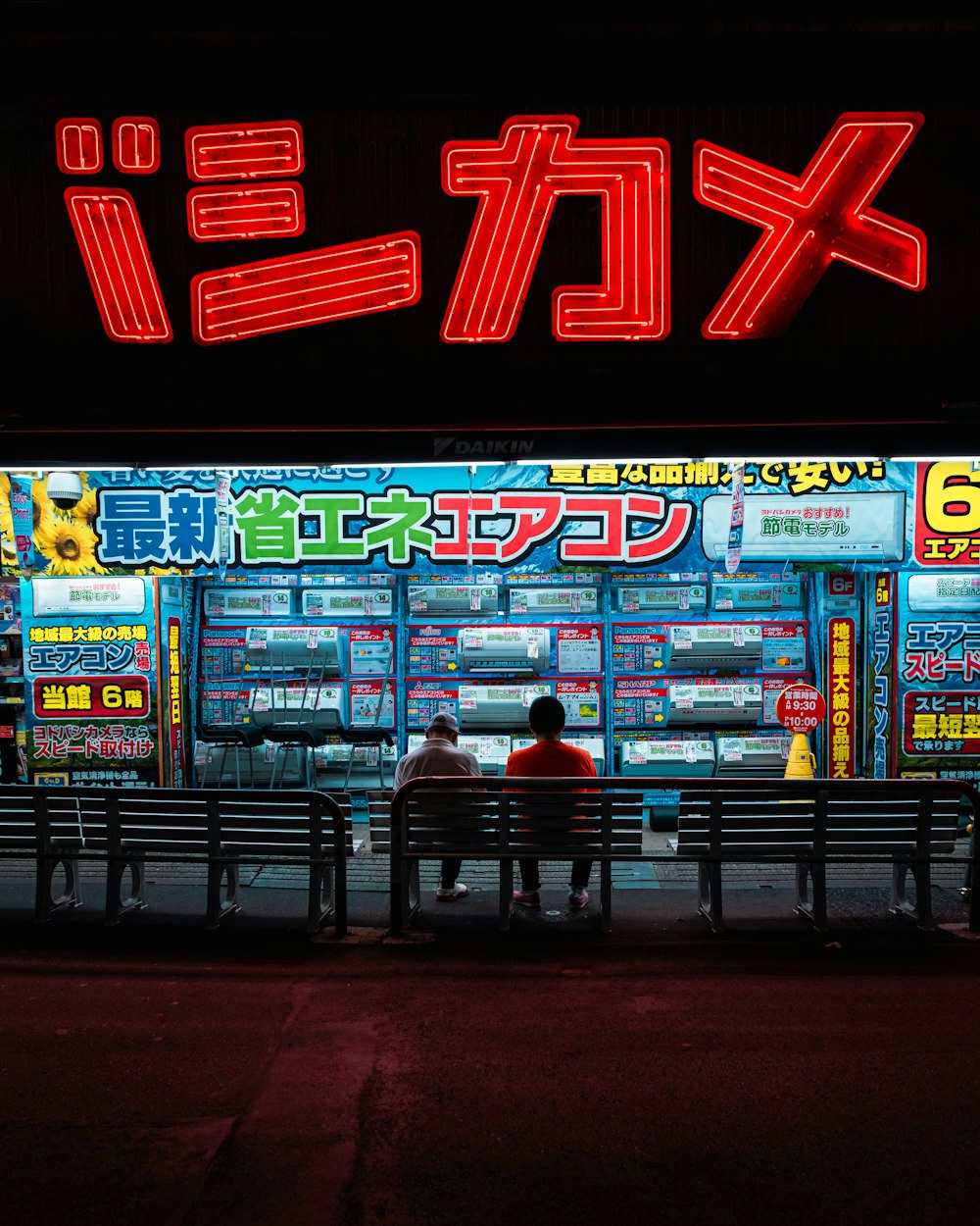 two person sitting on bench in front of store