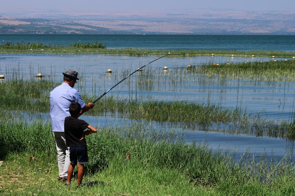 boy standing beside man fishing