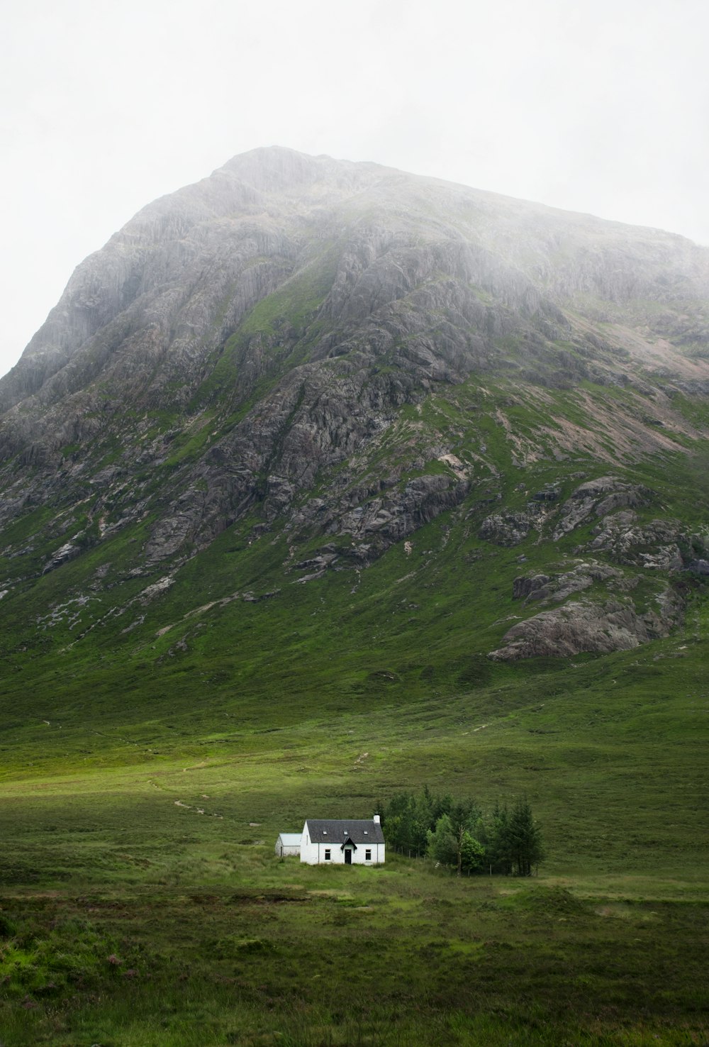 Casa de hormigón blanco y gris al lado de la montaña gris