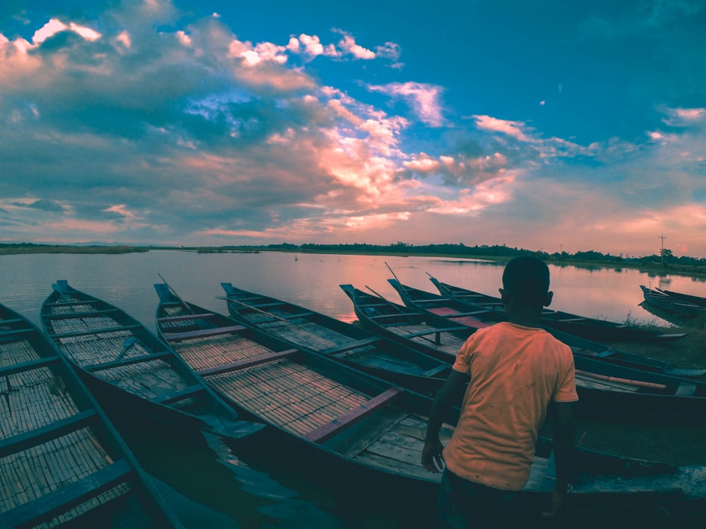 boy standing near brown boat