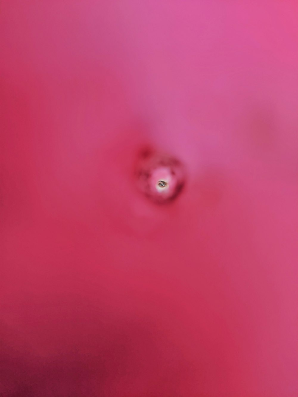 ein rosafarbener Hintergrund mit einem grünen Auge in der Mitte
