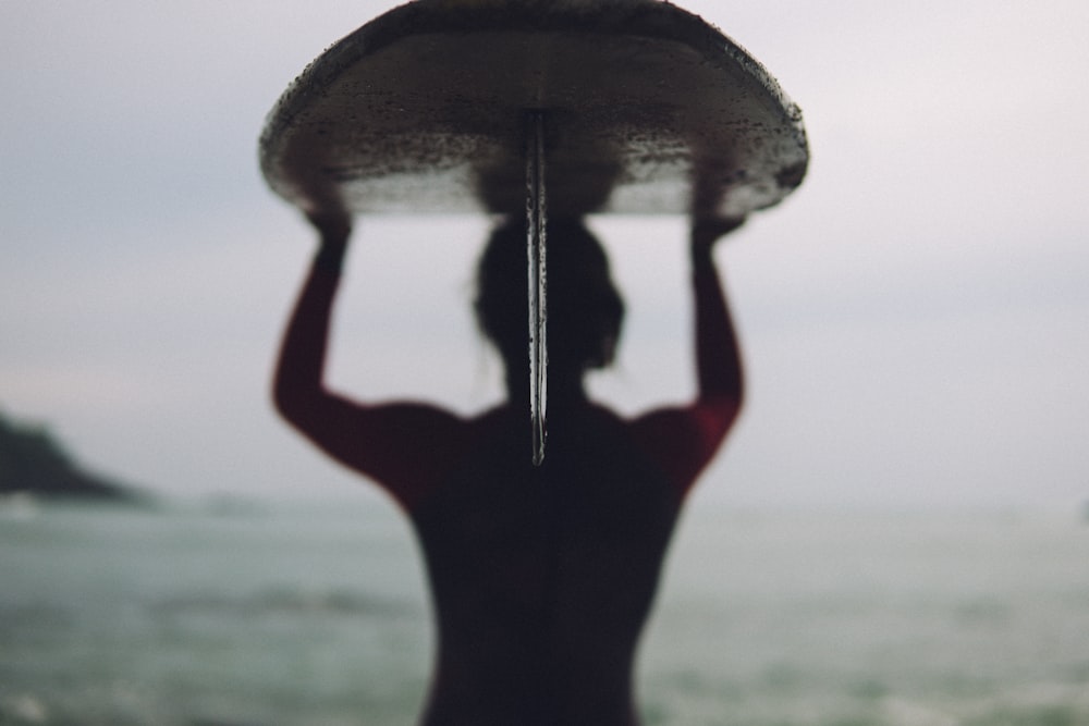 silhouette photography of woman carrying surfboard