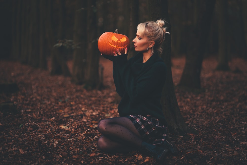 woman in black sweater holding pumpkin