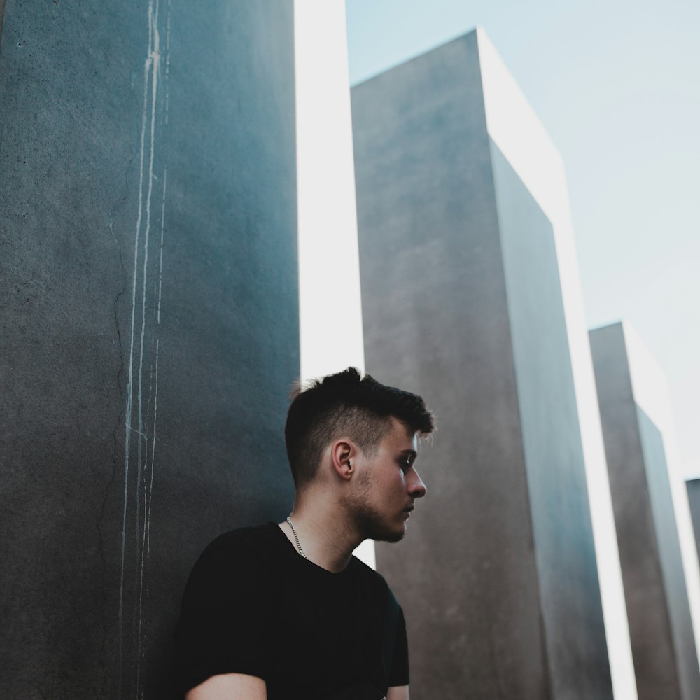 man in black crew-neck shirt leaning on wall