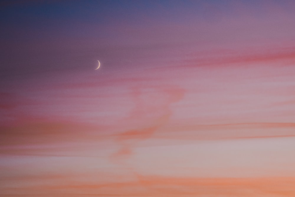 a plane flying in the sky at sunset