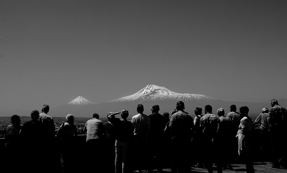 grayscale photo of people looking at icy mountain