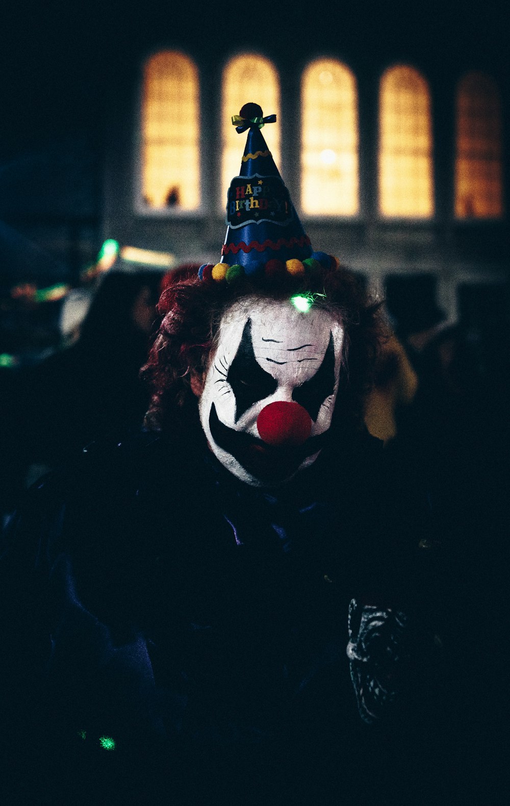 person wearing multicolored cone party hat and clown mask