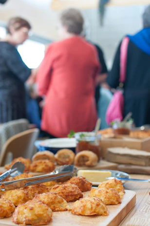 Smiling faces gathered around a table filled with homemade treats at a charity bake sale.