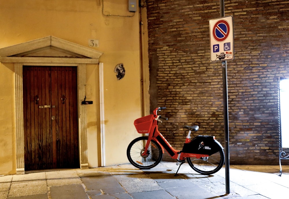 red and black bicycle parked near closed door house