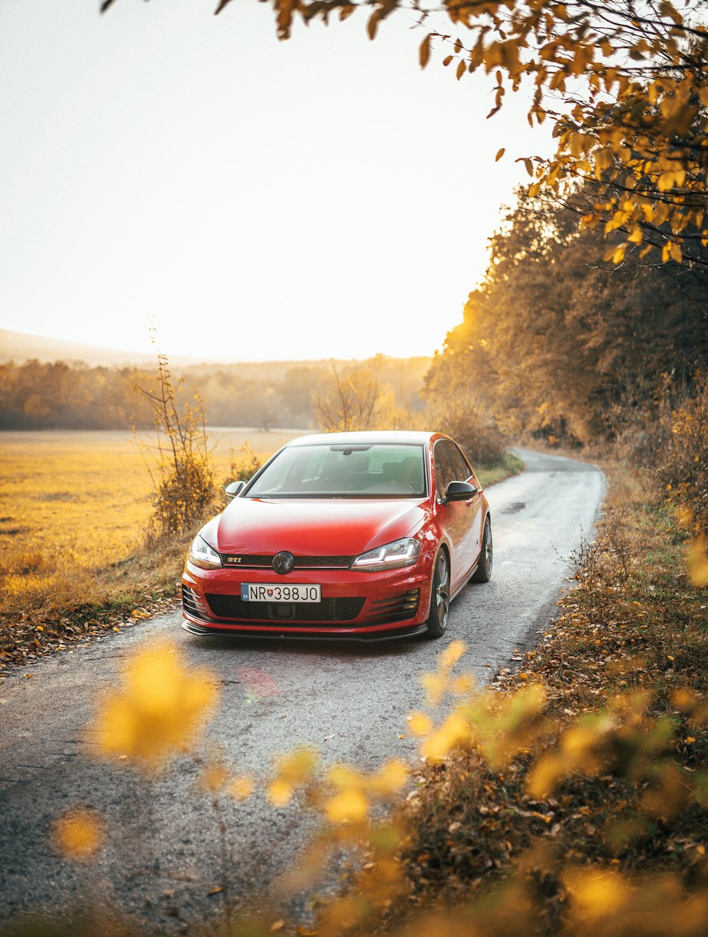 Rotes Auto, das an einer schmalen Straße vorbeifährt