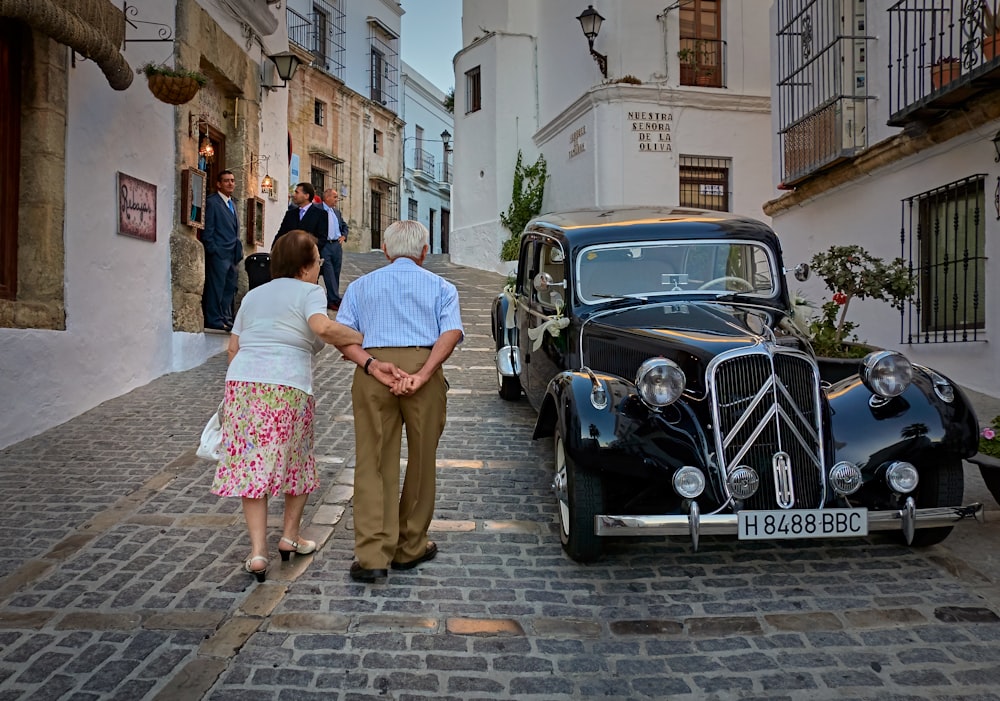 two person walking beside black vehicle