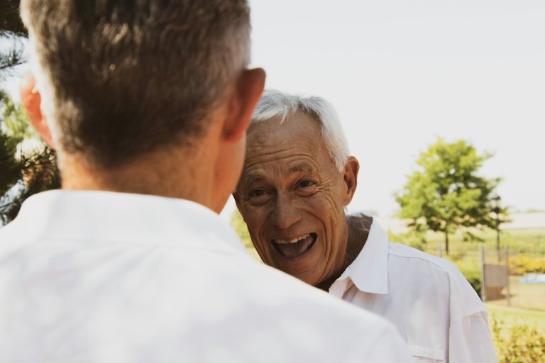 Adult son talking warmly with his elderly father outdoors