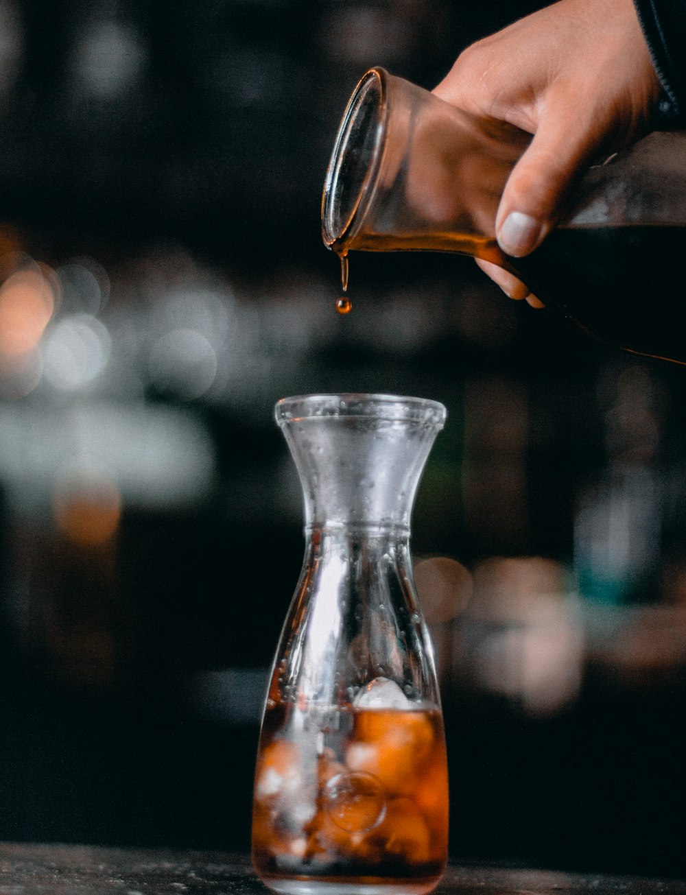 a person pours tea into a glass carafe